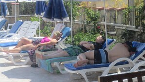 Un área junto a la piscina con sillones de descanso y sombrillas.