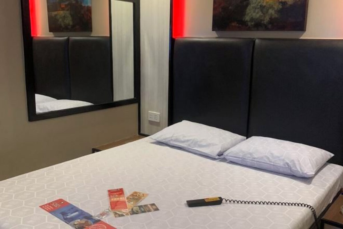 Una habitación de hotel con una cama, un espejo y una obra de arte en la pared.
