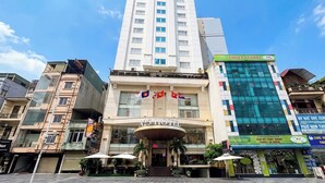 A hotel with a prominent entrance, flags, and a modern building adjacent to it. - A25 Signature Hotel (Hanoi)