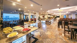 A buffet with various food items and a view of the cityscape through large windows. - A25 Signature Hotel (Hanoi)