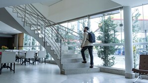 Un interior moderno con una escalera, ventanas amplias y una zona de estar.