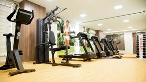 Un gimnasio con diferentes máquinas de ejercicio, un espejo y una pared con un cartel.