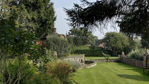 A well-maintained garden with a stone wall, a small pond, and lush greenery.