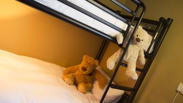 Una cama litera con dos osos de peluche: uno en la cama inferior y otro colgando del catre superior.