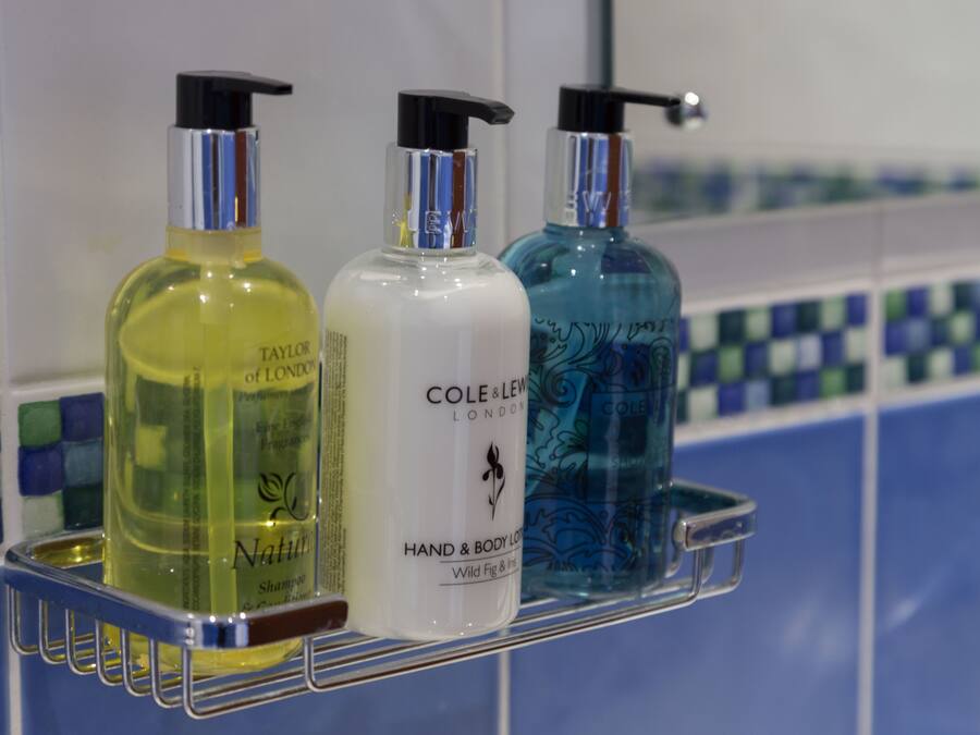 Tres botellas de loción para manos y cuerpo sobre una repisa metálica.