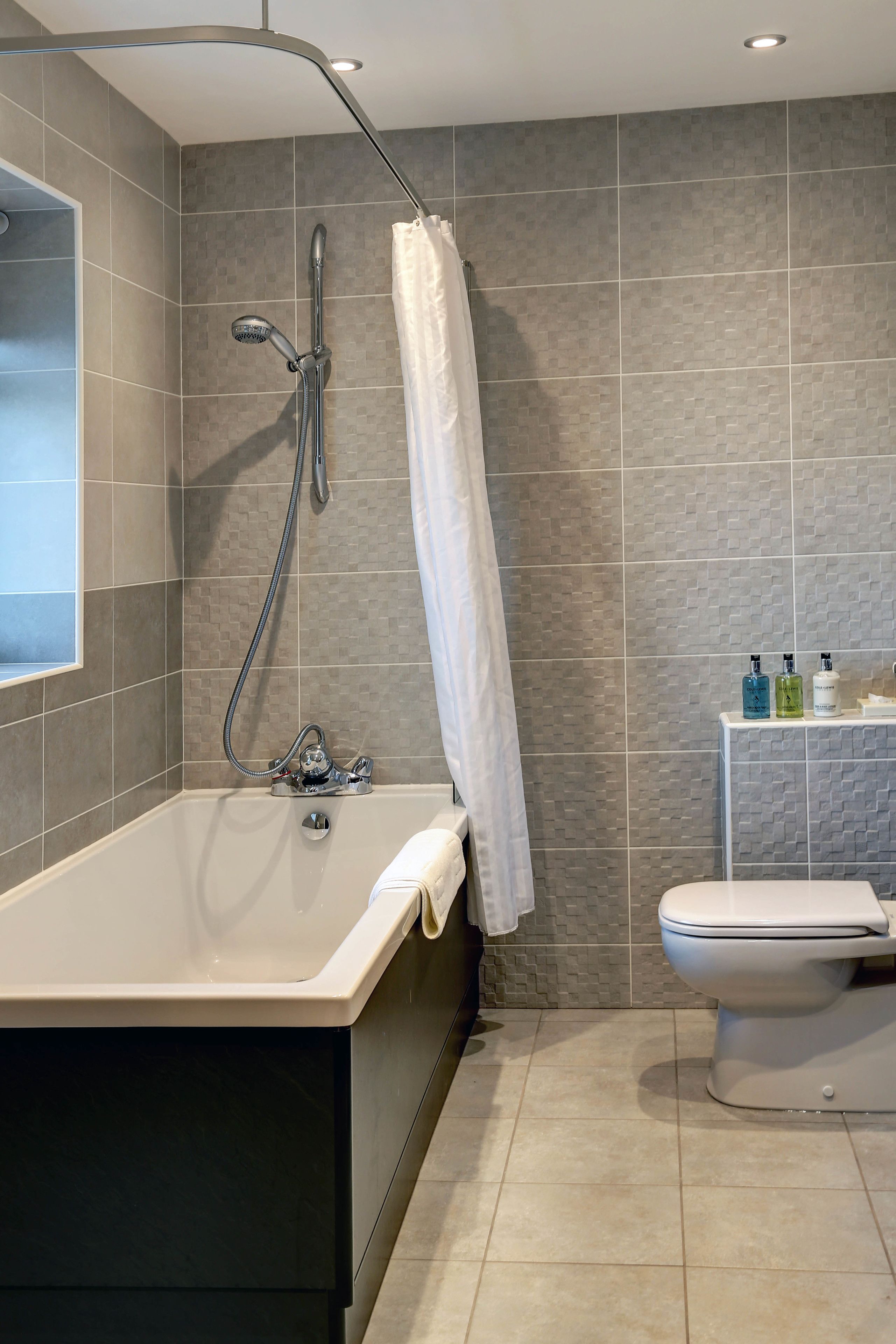 A modern bathroom with a bathtub, shower, and toilet.
