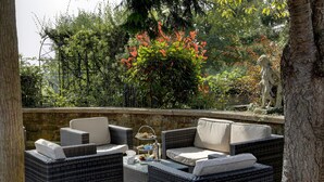 An outdoor seating area with wicker furniture and a stone wall backdrop.