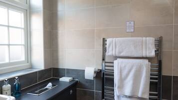 A modern bathroom with a white toilet, a sink with a mirror, and a towel rack with two white towels.