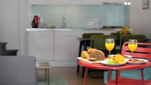 Zona de dinar amb taula preparada per l'esmorzar, incloent croissants, pa, rodanxes de taronja i gots de suc.