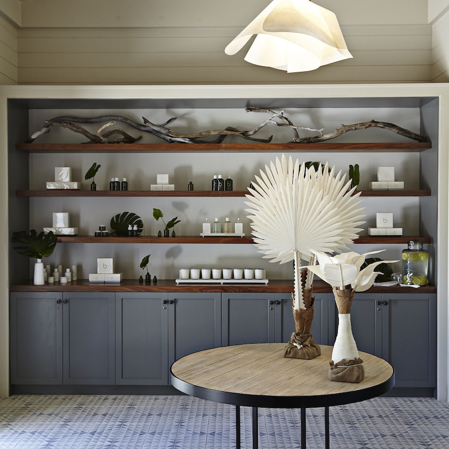 A room with a round table, shelves with various items, and a hanging light fixture.