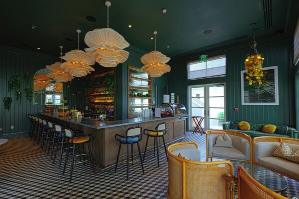 A bar area with a checkered floor, wicker furniture, and hanging light fixtures.