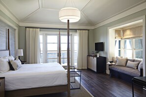 A hotel room with a large bed, a desk, a sofa, and a TV.