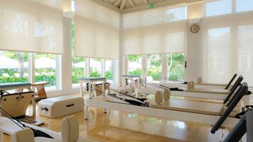 A Pilates studio with exercise equipment, large windows, and a wooden floor.