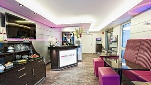 En modern hotellobby med en receptionsdisk, en sittgrupp och en stor spegel.
