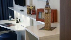 Ett rum med ett skrivbord, en tv, en modell av Big Ben och några böcker.