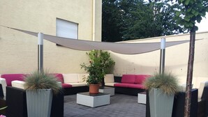An outdoor seating area with wicker furniture, a central potted plant, and a canopy. - Hotel Zum Rosengarten (Darmstadt)