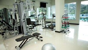 Un gimnasio con equipo de ejercicio variado, una pelota de ejercicio grande y un soporte para pesas.