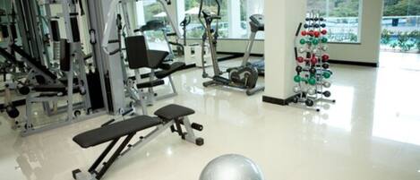 Ein Fitnessstudio mit verschiedenen Trainingsgeräten, einer großen Trainingskugel und einem Gewichtsständer.