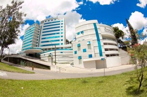 Um edifício moderno com fachada curva, vários andares e uma entrada destacada com rampa.