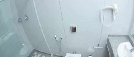 A modern bathroom with a glass shower enclosure, a toilet, and a sink with a mirror.