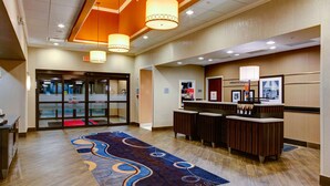 A hotel lobby with a reception desk, a patterned carpet, and a glass door entrance. - Hampton Inn & Suites Columbus (Columbus)