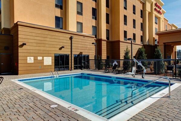 A hotel with a swimming pool, outdoor seating, and a sign indicating a handicap accessible area.