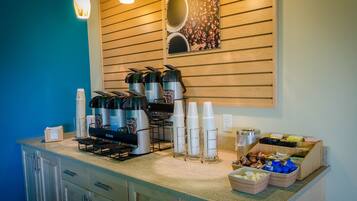 A coffee station with multiple coffee makers, cups, and a coffee bean display.