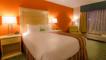 A hotel room with a large bed, two bedside tables, a chair, and a window with curtains.