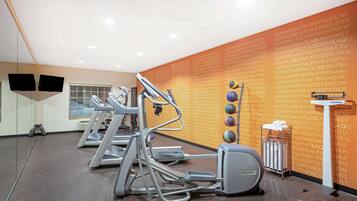 A gym with treadmills, elliptical machines, and a wall with motivational quotes.