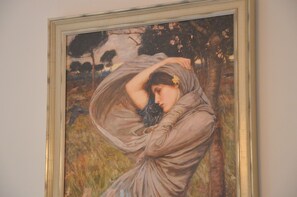 A framed painting of a woman in a flowing dress, set against a backdrop of trees and a cloudy sky. - Guesthouse Pickery (Bruges)