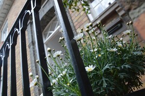 A black metal gate with white flowers and green foliage. - Guesthouse Pickery (Bruges)