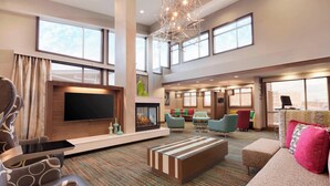 A spacious hotel lobby with a large flat-screen TV, a fireplace, comfortable seating areas, and large windows offering views. - Residence Inn by Marriott San Angelo (San Angelo)