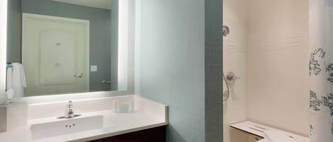 A bathroom with a white sink, mirror, and shower area.