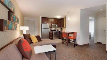 A hotel room with a living area, kitchenette, and a separate dining area.