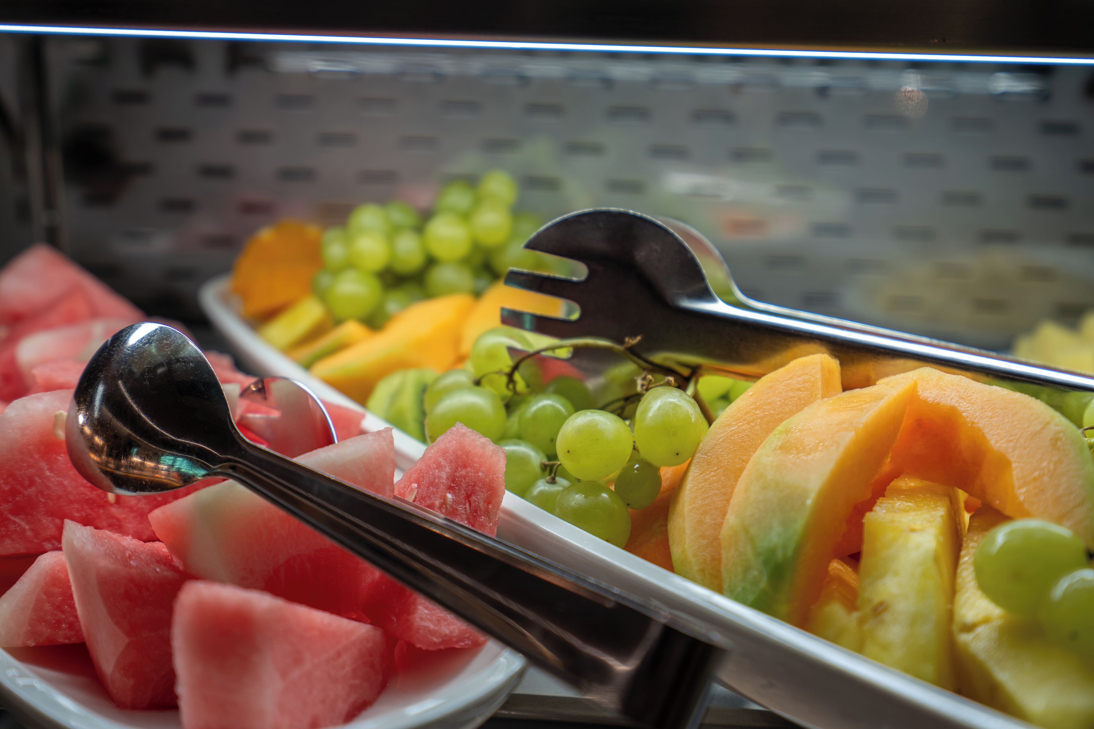 A buffet with various fruits including watermelon, grapes, and cantaloupe.