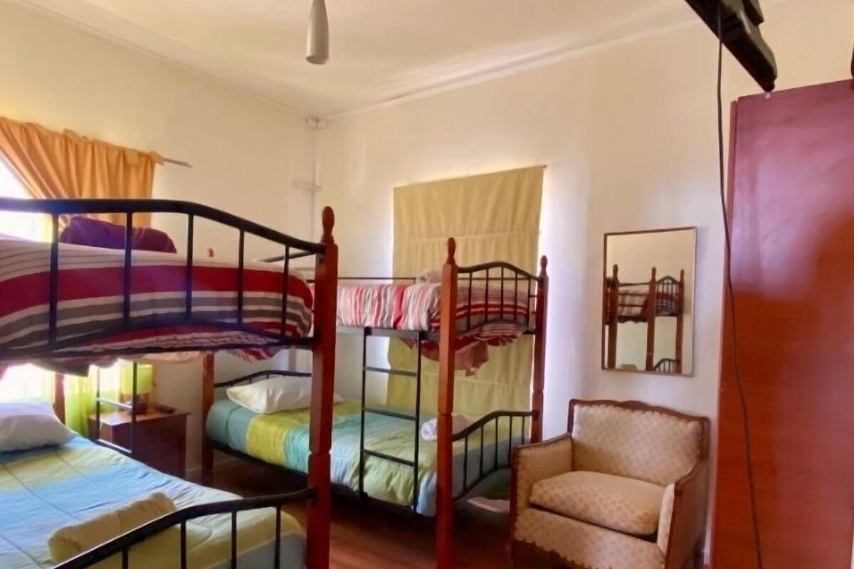 A room with bunk beds, a chair, a desk, and a ceiling fan.