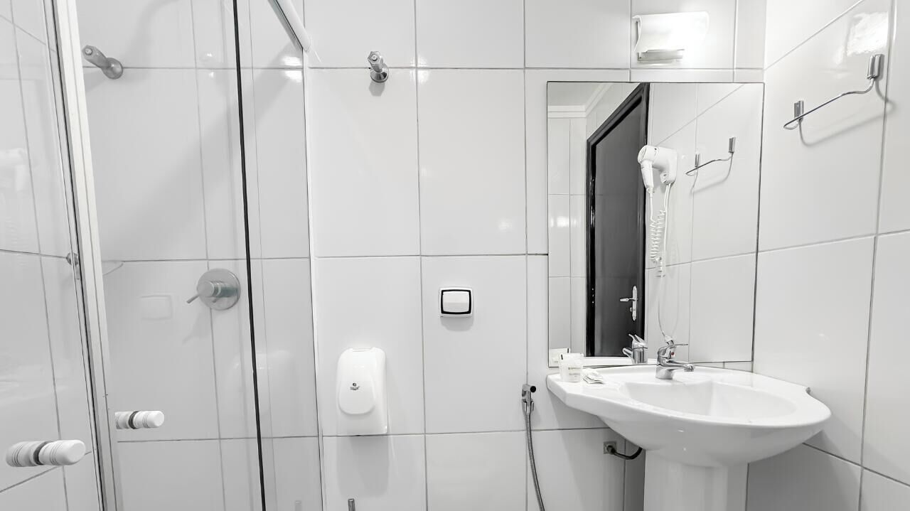 A modern bathroom with a glass shower enclosure, a white sink, and a mirror.