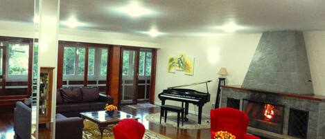 A spacious living room with a piano, a fireplace, and a red armchair.