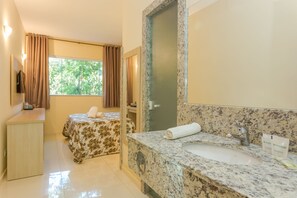 A hotel room with a bed, a bathroom with a sink and mirror, and a window with curtains. - Hotel Fazenda Golden Park Campos do Jordão (Campos do Jordão)