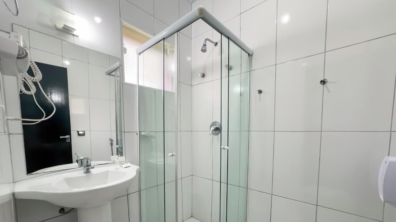 A modern bathroom with a glass-enclosed shower, a white sink, and a mirror.