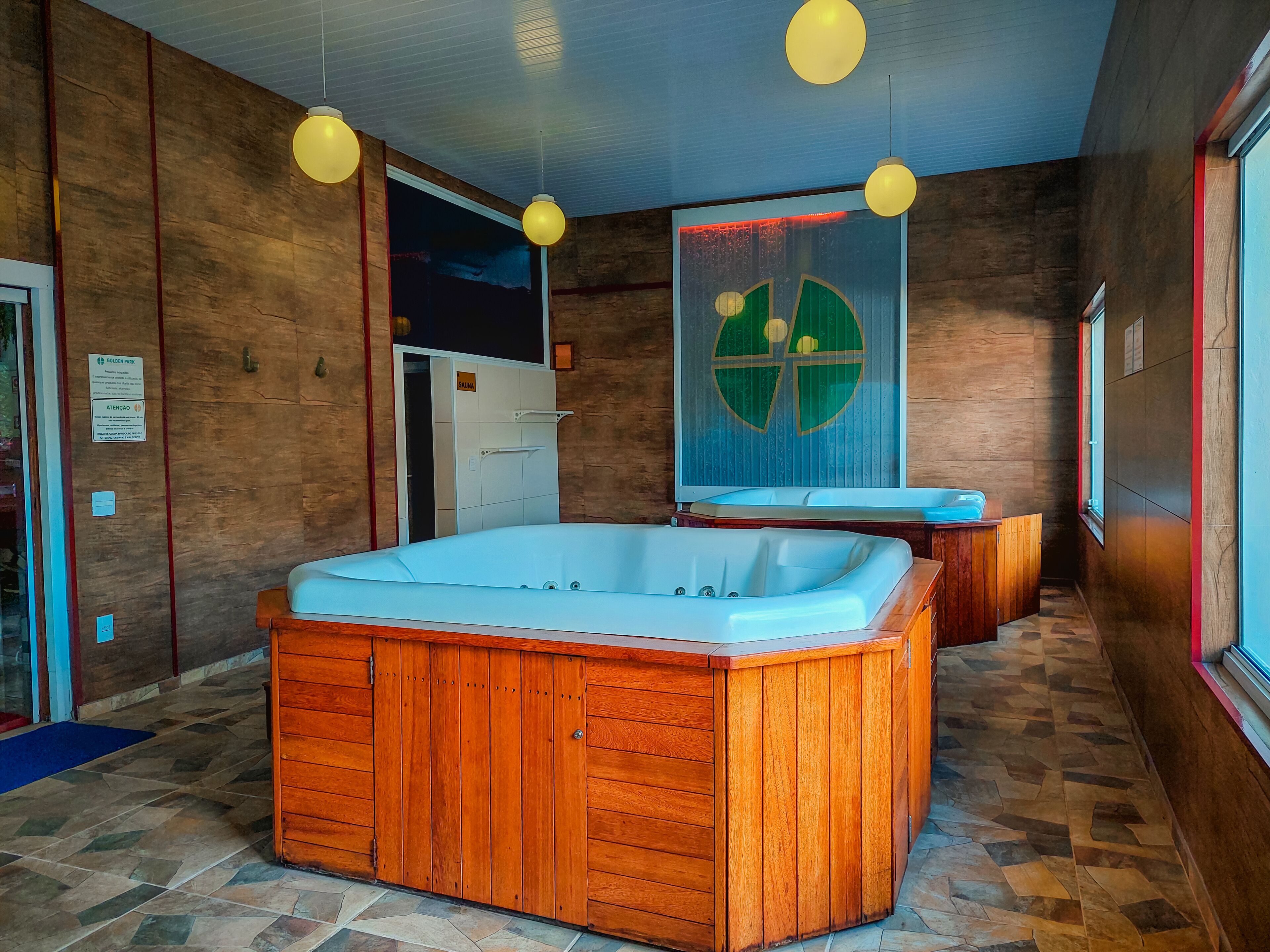 Une salle de spa dotée d’une baignoire en bois, d’un sauna et d’une grande fenêtre.