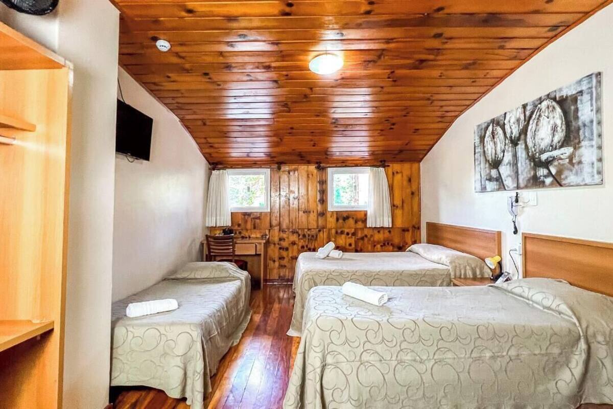 A room with two beds, wooden walls, a ceiling fan, and a painting on the wall.