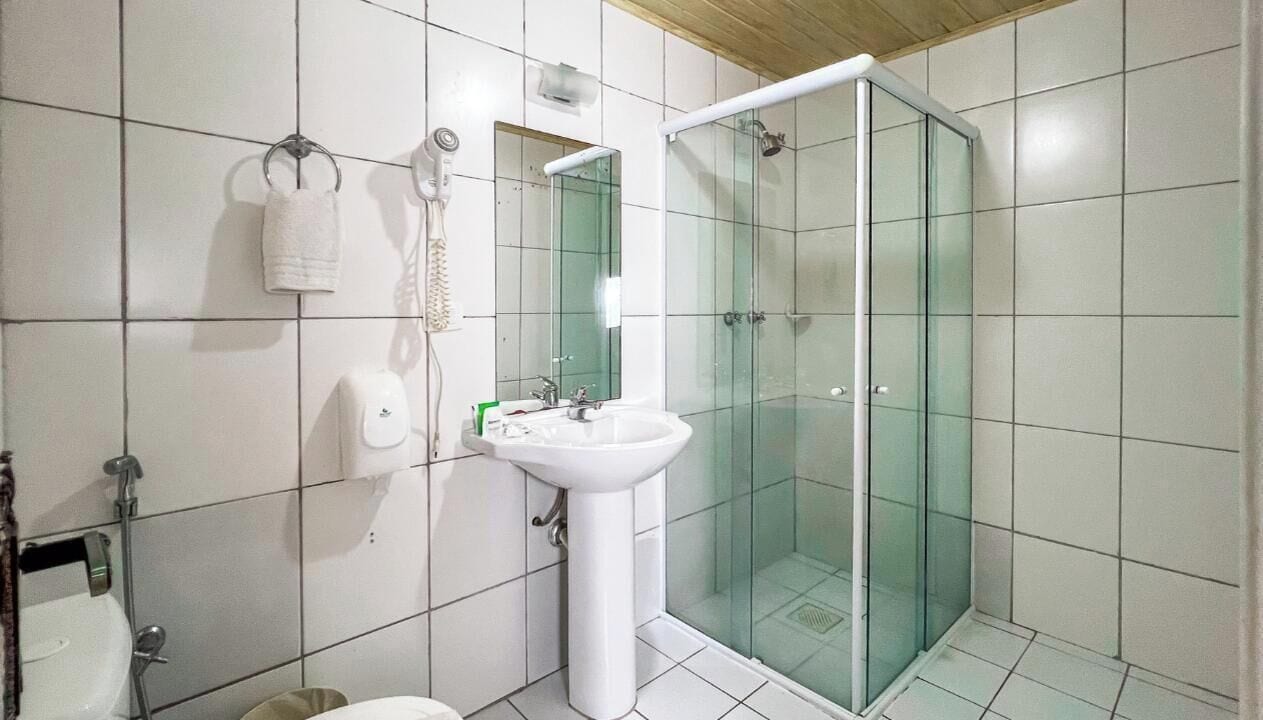 Une salle de bain avec une douche à parois de verre, un lavabo blanc et un porte-serviettes.