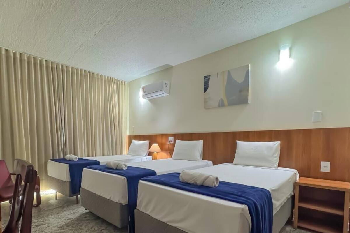A hotel room with two beds, a desk, a chair, and a window with curtains.