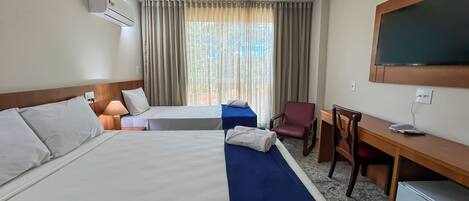 A hotel room with two beds, a desk, a chair, a TV, and a window with curtains.