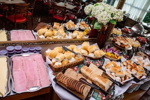 Un buffet proposant une variété de plats, notamment du pain, des pâtisseries et de la viande.
