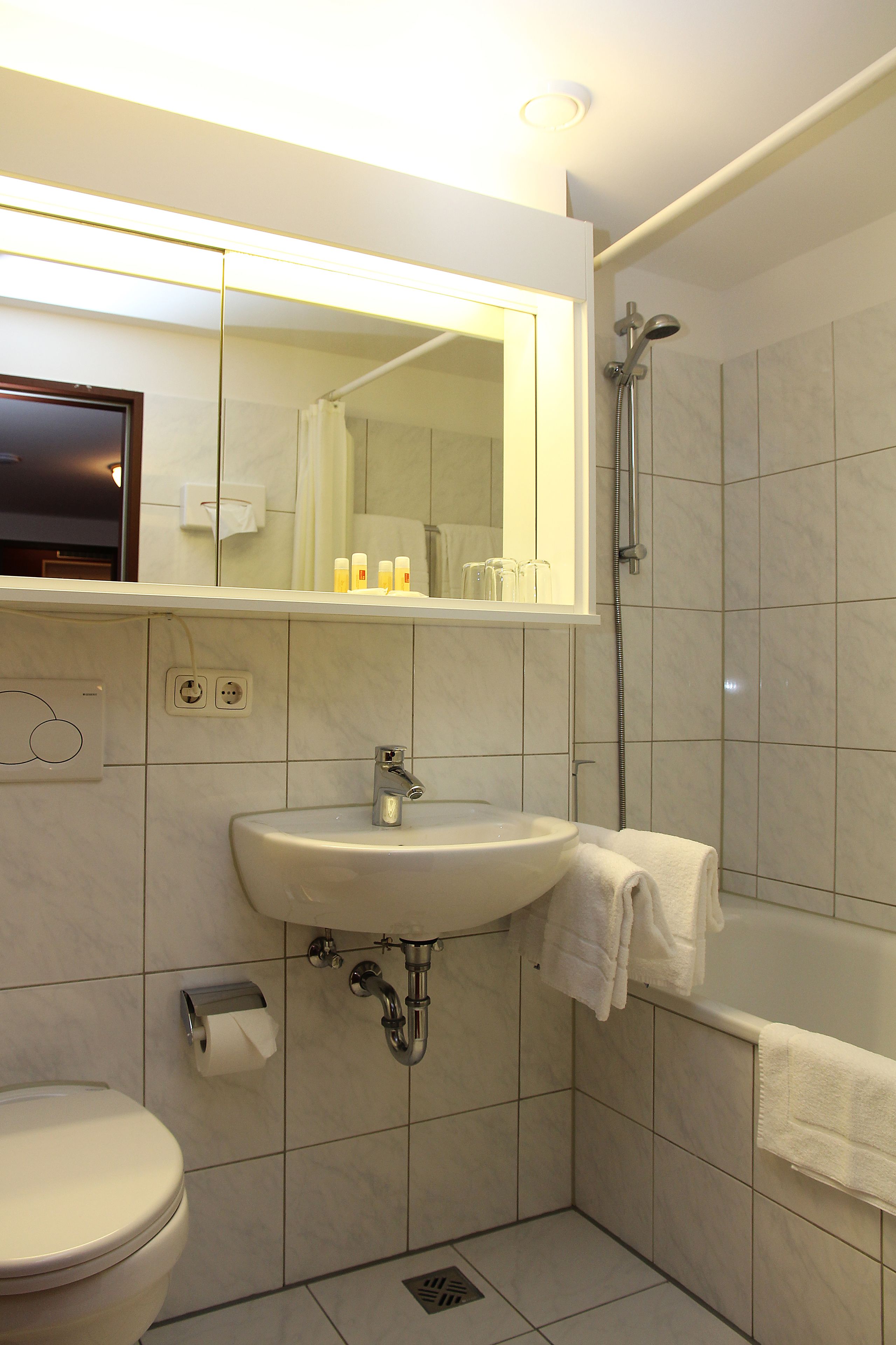 Een moderne badkamer met een wastafel, toilet en douche.