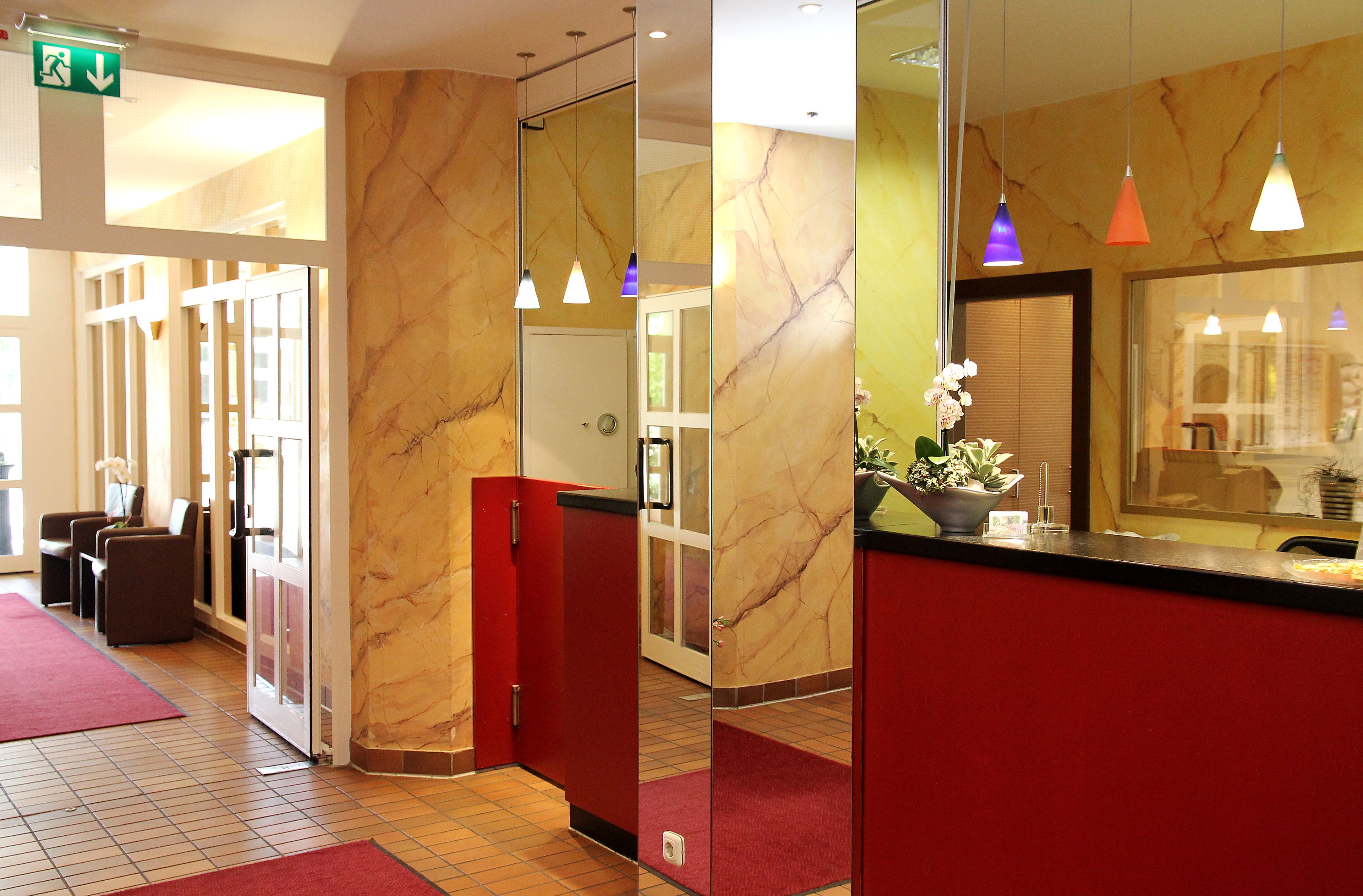 Uma área de recepção de hotel com paredes de mármore, um balcão vermelho e um tapete vermelho.