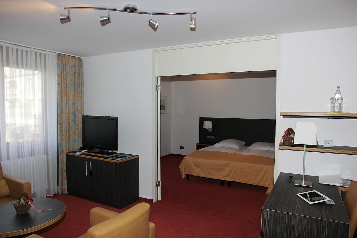 A hotel room with a bed, a TV, a desk, and a chair.