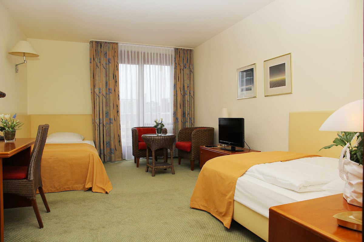 A hotel room with two beds, a TV, a desk, and a chair.